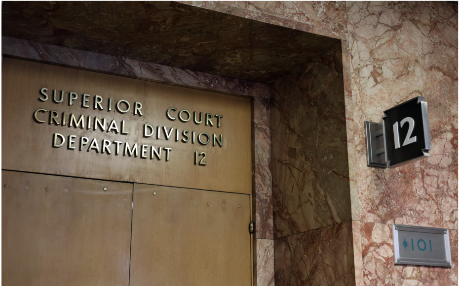 Double doors labeled "Superior Court Criminal Division Department 12" in a building with marble walls; a sign with the number 12 is on the adjacent wall.