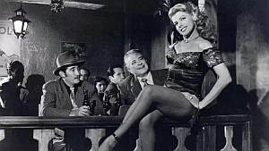 A woman in a sequined dress sits on a bar railing, posing, while two men seated at the bar look at her in a dimly lit, vintage-style setting.