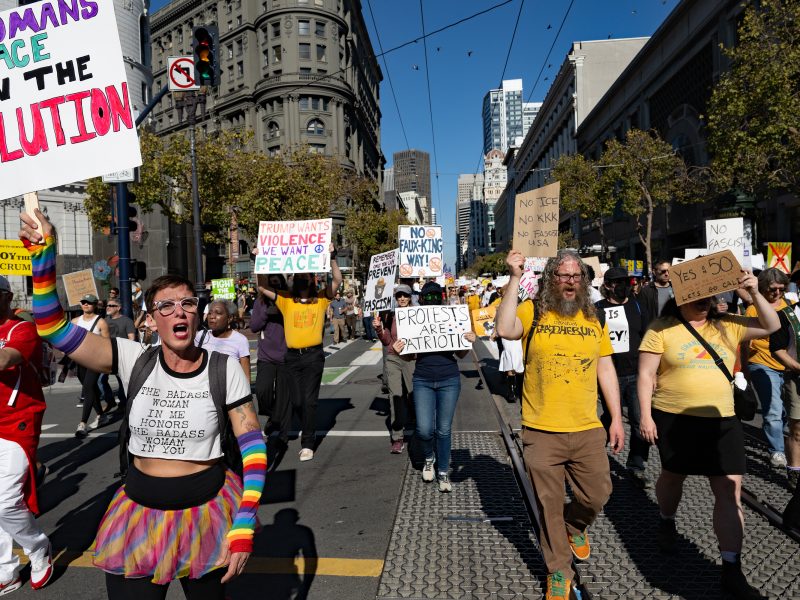 A group of people march down a city street holding protest signs advocating for women's rights and reproductive freedom.