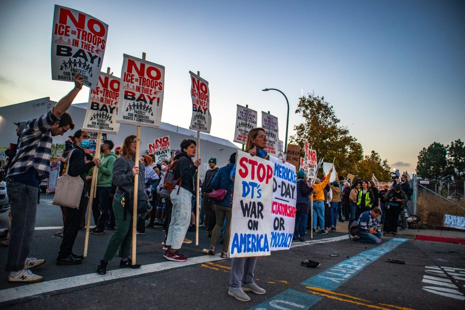 A group of protesters hold signs opposing ICE and troops in the Bay Area, with messages like "No ICE+Troops in the Bay" and "Stop DT’s War on America.