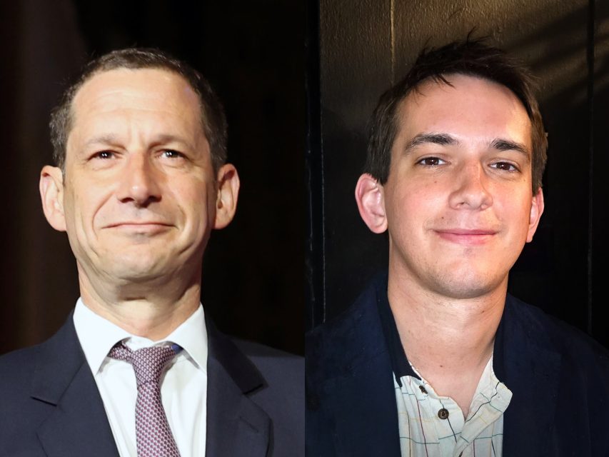 Two men are pictured side by side; the man on the left is wearing a suit and tie, while the man on the right is dressed in a casual shirt and jacket, both facing the camera.