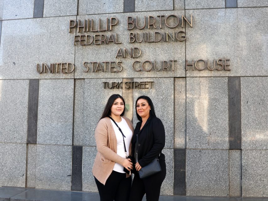 Two women standing in front of the Phillip Burton Federal Building and United States Court House on Turk Street.