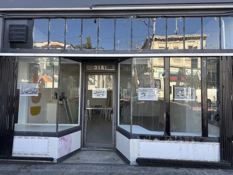 Streetfront view of a vacant storefront with large windows, black trim, address number 3151, and signs in the windows advertising commercial space for lease.