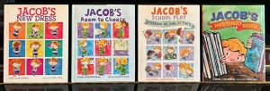 Four children’s books titled “Jacob’s New Dress,” “Jacob’s Room to Choose,” “Jacob’s School Play,” and “Jacob’s Missing Book” are displayed side by side on a shelf.