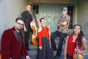 Five musicians pose on steps, holding various instruments including a double bass, flute, and violin, in front of a large closed door.