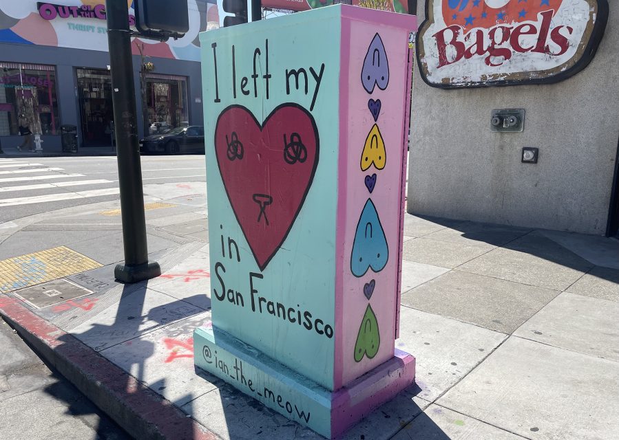 A painted utility box on a city sidewalk reads "I left my [cat drawing in heart] in San Francisco" with colorful hearts and the Instagram handle @iam.thee.meow.