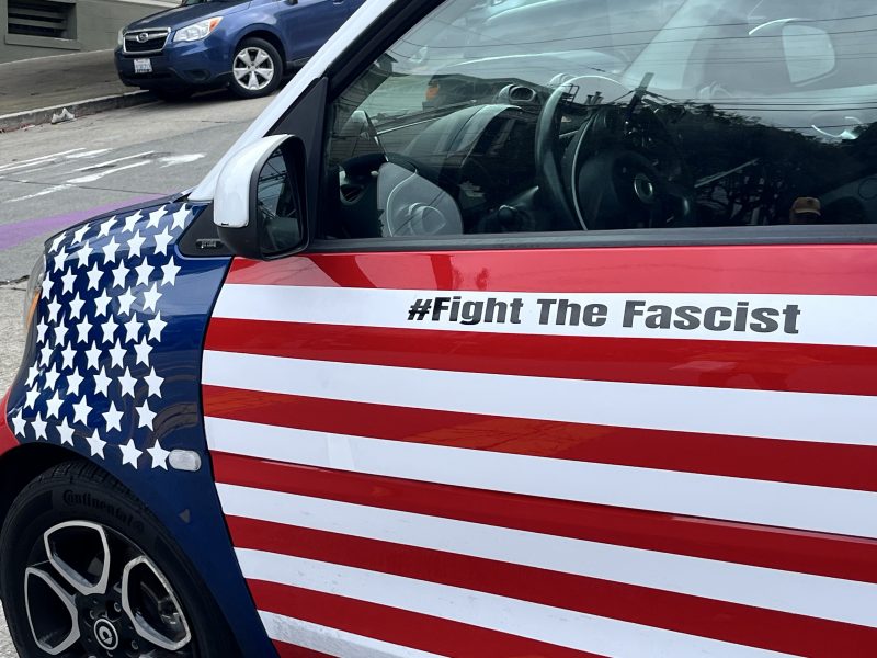 Car door decorated with the American flag pattern and the text "#Fight The Fascist" written above the stripes.