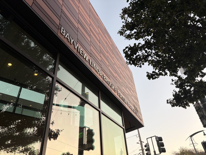 Exterior view of the Bayview Linda Brooks-Burton Branch Library building with large windows and tree branches visible.