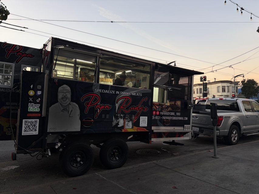 A black food truck labeled "Papa Rady's" is parked on Bayview 3rd Street at dusk, with a person inside serving food and a gray pickup truck parked behind it.