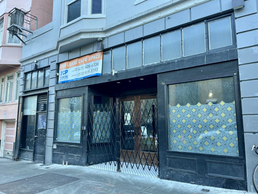 Storefront with metal security gates and patterned window coverings, displaying a "For Lease Cafe Space" sign with contact information above the entrance.