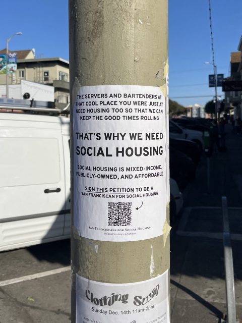 A flyer on a street pole advocates for social housing, stating its importance for servers and bartenders, and encourages signing a petition for mixed-income, publicly-owned housing.