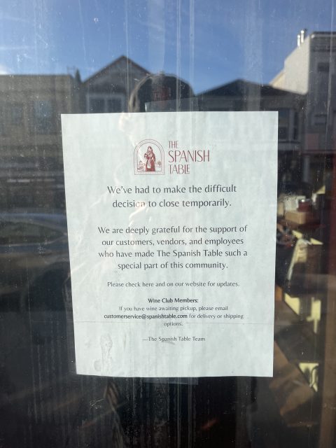 A printed notice on a window announces The Spanish Table is temporarily closed and thanks customers, vendors, and employees for their support.