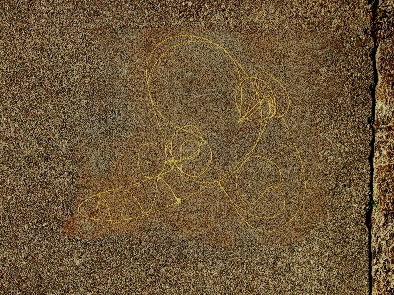 Yellow chalk drawing with looping and circular lines on a cracked concrete sidewalk.