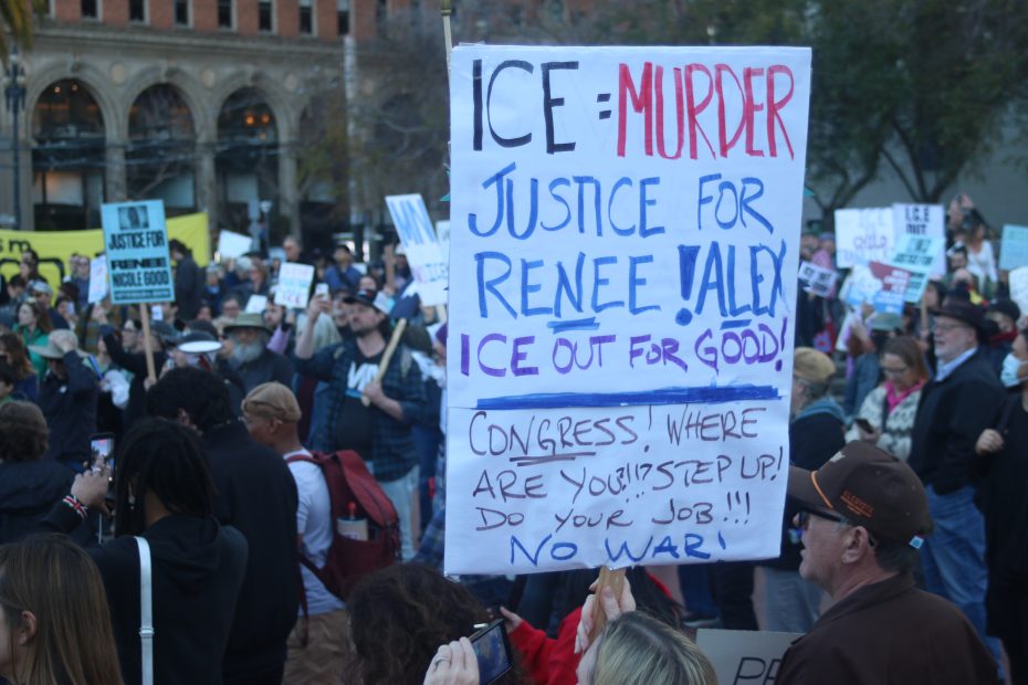 A crowd of protesters holds signs, including one large sign reading "ICE = Murder, Justice for Renee/ Alex, ICE out for good! Congress, do your job!! No war!.
