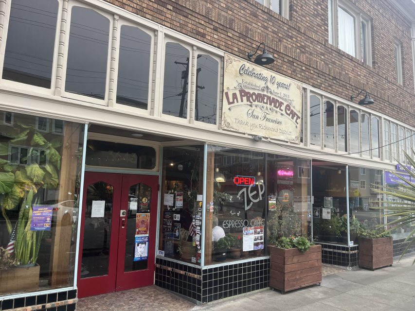 Street view of La Provence Café with a large sign above the entrance, red double doors, and a lit neon “OPEN” sign in the window.