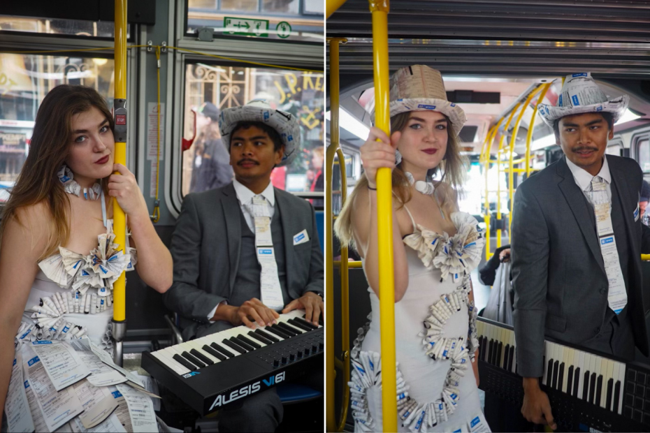 Two people on a bus wear formal outfits made from parking tickets; the woman stands by a pole, while the man alternates between sitting and standing with a keyboard.