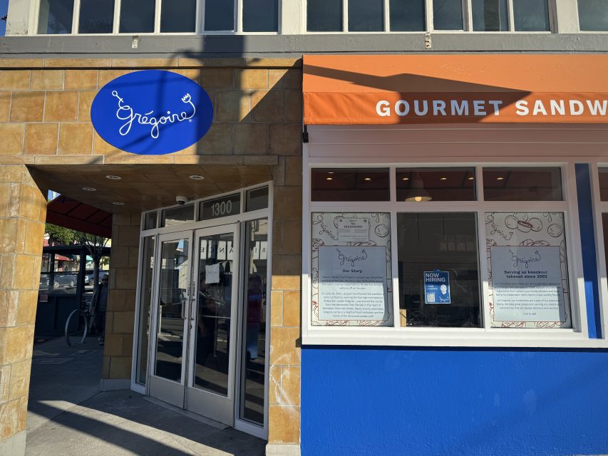 A storefront with a blue "Grégoire" sign and an orange "GOURMET SANDWICHES" awning above windows displaying printed menus.