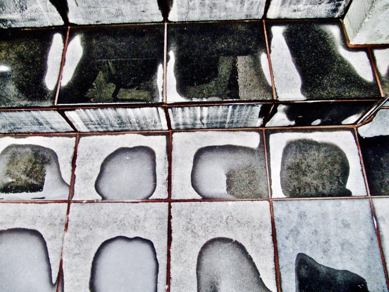 Black and white tiled steps with irregular wet and dry patches on the surface, creating an abstract pattern.