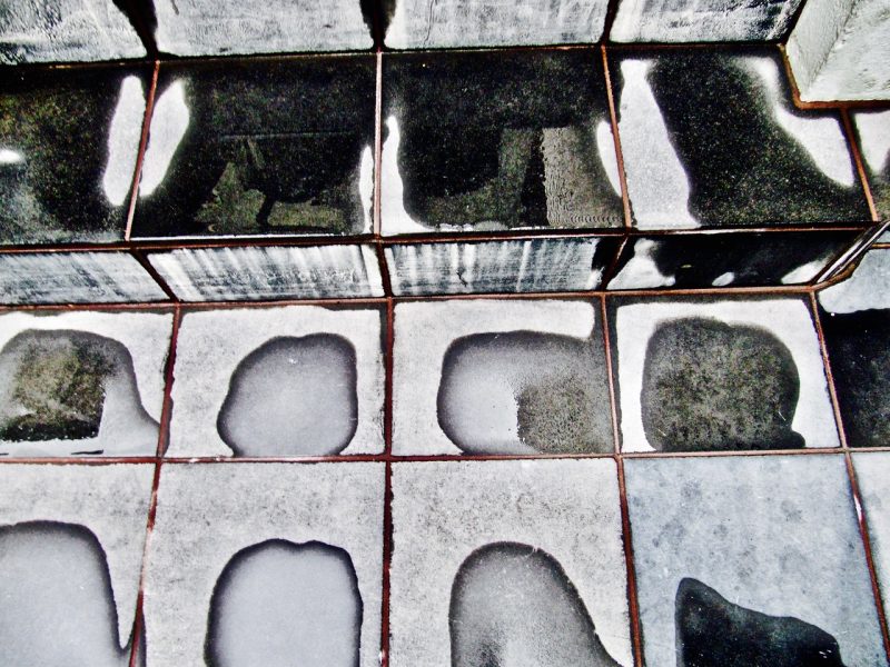 Black and white tiled steps with irregular wet and dry patches on the surface, creating an abstract pattern.