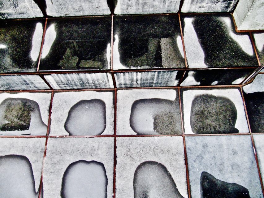 Wet and dry black-and-white tiled steps, showing irregular patches where the tiles are drying unevenly.