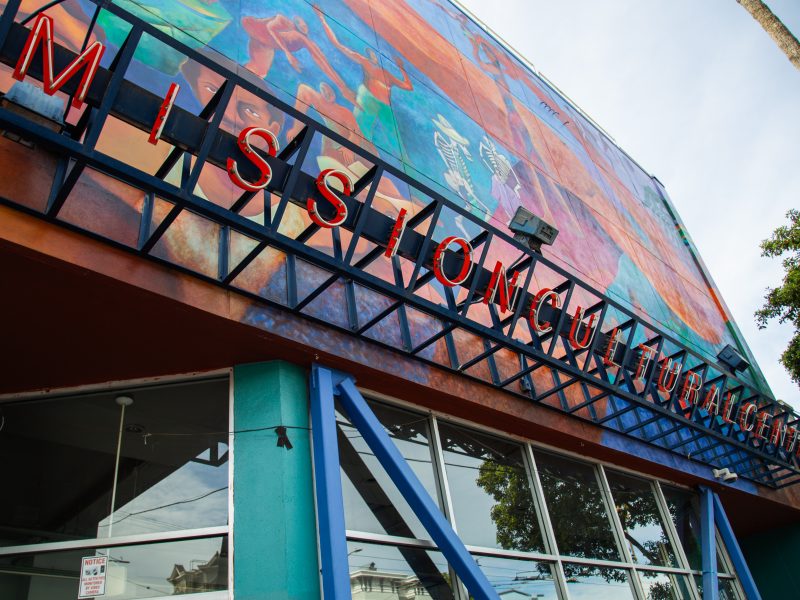 Exterior view of the Mission Cultural Center for Latino Arts with colorful mural and red marquee letters on the building facade.
