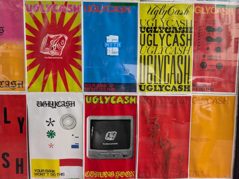 A grid of colorful posters, mostly reading "UGLYCASH" and "Your bank won't do this," with various graphic designs and fonts against a wall.