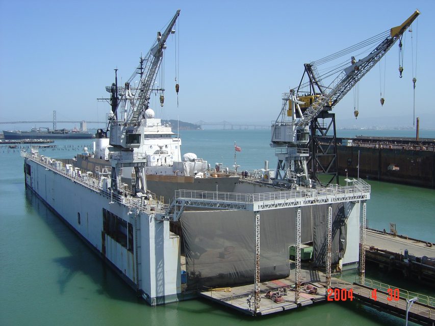 A large floating dry dock with a ship inside is moored at a port; two cranes are positioned on the structure. The date on the photo is April 30, 2004.