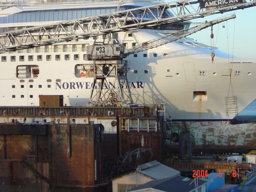 A large cruise ship named "Norwegian Star" docked at a shipyard, with a crane and rusted structures in the foreground. Date stamp: 2004-05-08.