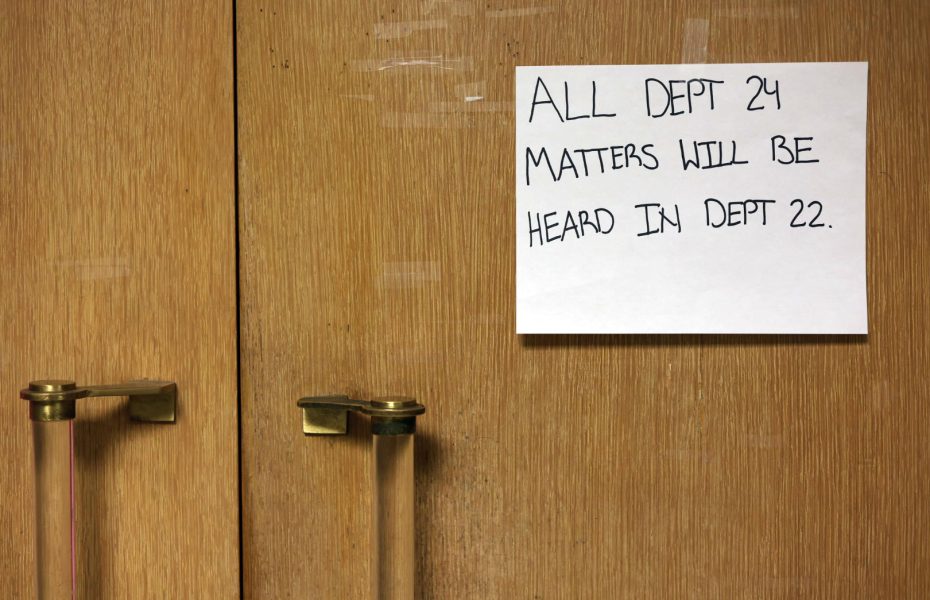 A handwritten sign on wooden doors reads, “ALL DEPT 24 MATTERS WILL BE HEARD IN DEPT 22.”.