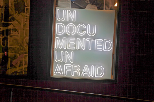 A neon sign in a window displays the words "UN DOCUMENTED UN AFRAID" in white letters.