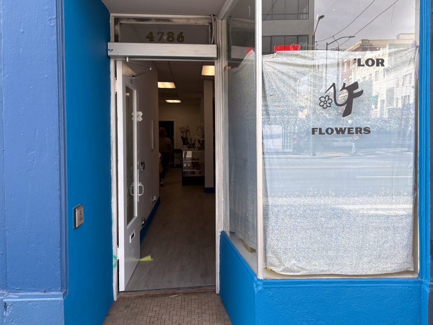 A storefront with an open door at 4786; the adjacent window displays a partially covered sign reading “FLOWERS” with floral graphics.