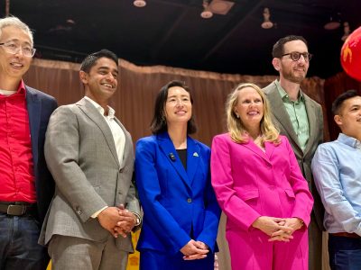 Six people stand side by side indoors, dressed in business attire, posing and smiling for a group photo.