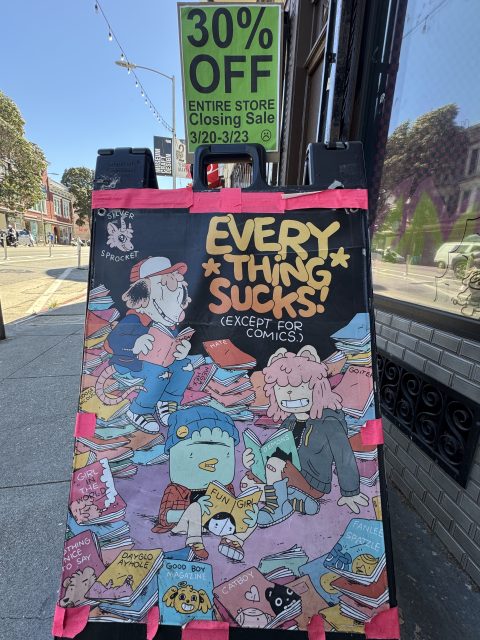 A sidewalk sign shows a "30% OFF Entire Store Closing Sale" notice above a comic-style poster reading "Everything Sucks! (Except For Comics.)" with cartoon characters and books.