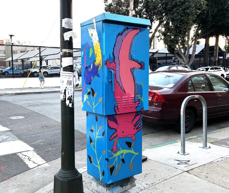 A utility box painted with colorful axolotls and aquatic plants stands on a city sidewalk near a parked car and bike rack.