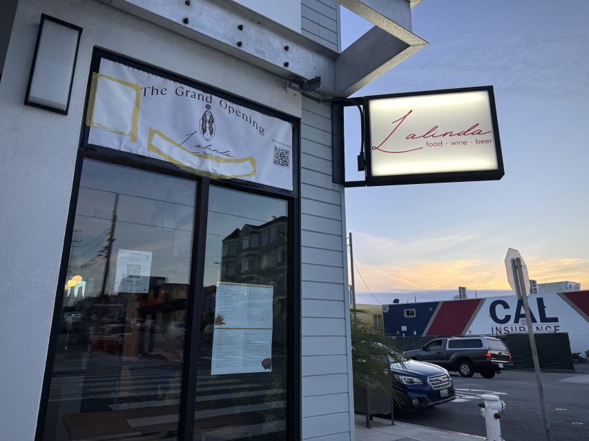 Exterior of Lalinda restaurant with a grand opening banner above the door and a lit sign reading "Lalinda food·wine·beer" at sunset.