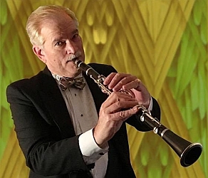 A man in a tuxedo plays a clarinet against a patterned yellow background.