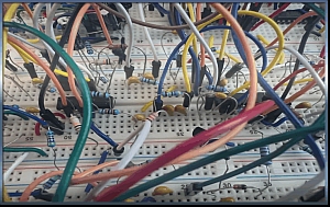 Close-up of a breadboard with multiple interconnected wires, resistors, and electronic components arranged for a circuit prototype.